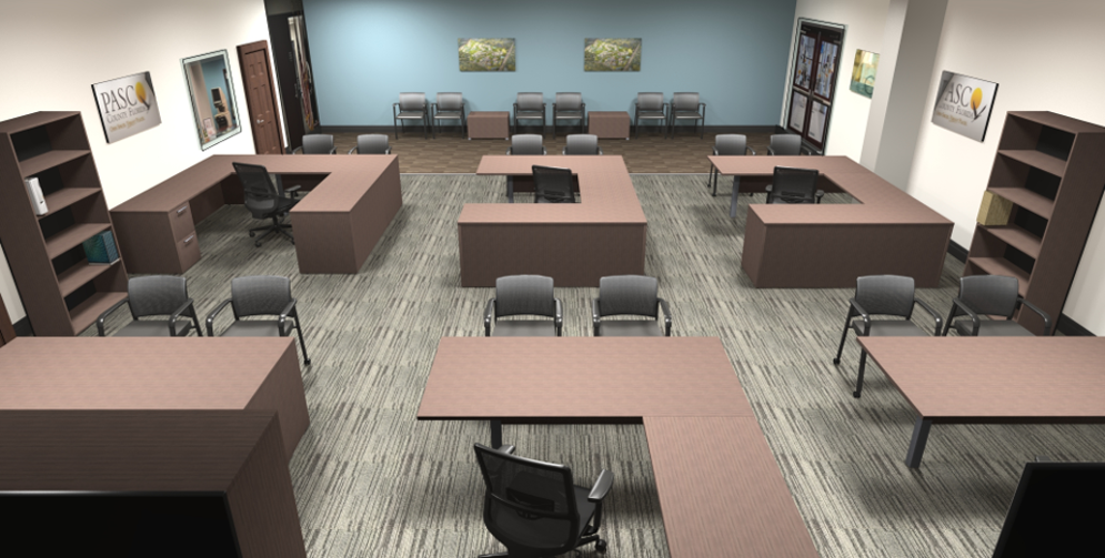 Open office workspace with multiple U-shaped brown desks, gray chairs, and bookshelves; a teal wall with framed art at the back.